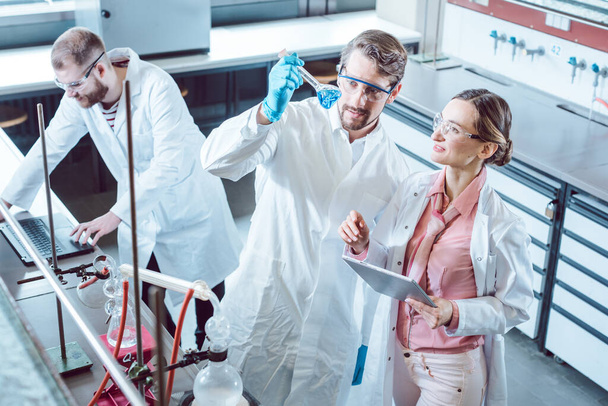 Команда ученых во время эксперимента в лаборатории рассматривает тестовое стекло - Фото, изображение