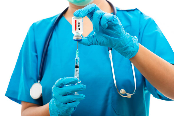 Female nurse with stethoscope puts on rubber gloves and wear medical face mask, woman doctor in blue uniform holding syringe . and COVID-19 vaccine, isolated white background, medical health concept - 写真・画像