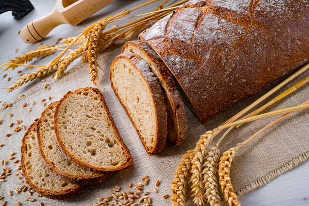fresh baked bread with ears of wheat on a wooden background - Foto, immagini