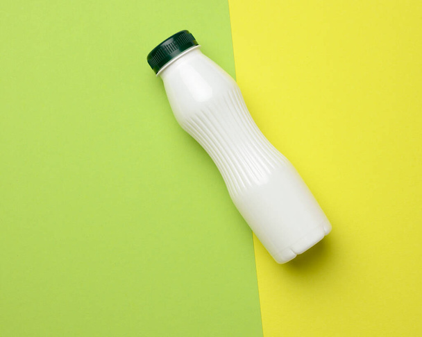 white plastic bottle for milk on a green background, container for liquid products, flat lay - Valokuva, kuva