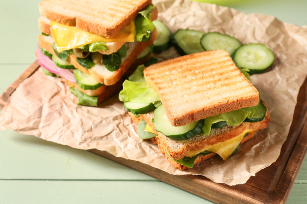 Board with tasty sandwiches on color wooden background, closeup - Photo, Image