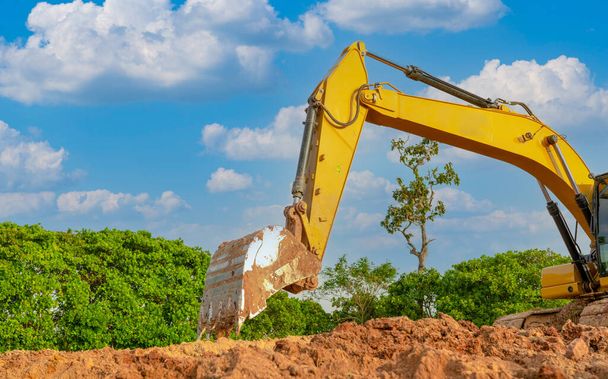 Backhoe working by digging soil at construction site. Bucket of backhoe are digging soil. Crawler excavator digging on soil. Excavating machine. Earth moving machine. Excavation vehicle. - Photo, image