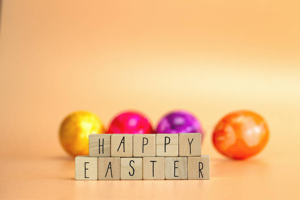 Happy Easter written with pastel colored orange background and colorful fainted Easter eggs, Bright fresh colors, Spring,Easter Holiday, greeting card concept with copy space space for text - Photo, image