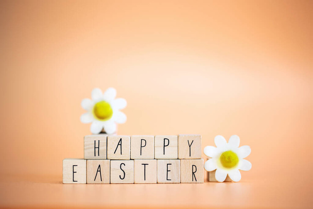 Happy Easter written with pastel colored orange background and bright spring flowers, greeting card,spring,colors,Easter Holiday concept copy space space for text - Fotografie, Obrázek