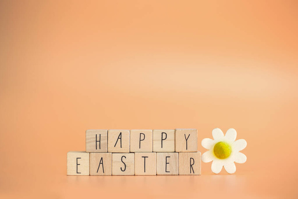 Happy Easter written with pastel colored orange background and bright spring flowers, greeting card,spring,colors,Easter Holiday concept copy space space for text - Photo, image