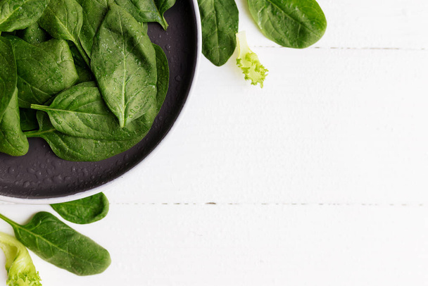 Bowl with fresh green salad leaves, spinach, lettuce, basil on a white background. Healthy vegetarian eating concept. High quality photo - Фото, зображення