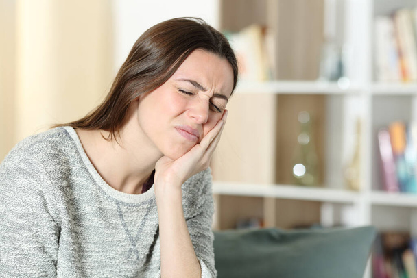 Stressed woman suffering toothache complaining touching cheek on a couch at home - Foto, Imagem