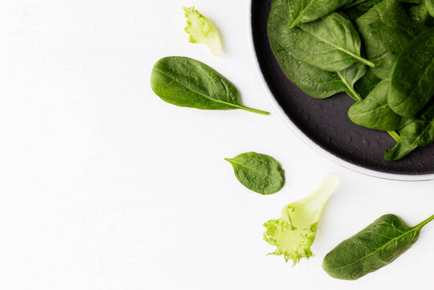 Bowl with fresh green salad leaves, spinach, lettuce, basil on a white background. Healthy vegetarian eating concept. High quality photo - Photo, image