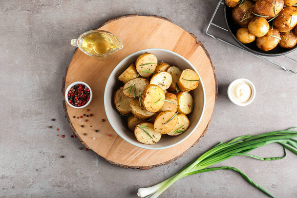 Ciotola con patate al forno e rosmarino su fondo grigio - Foto, immagini