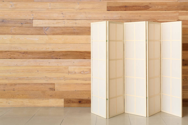 Stylish folding screen near wooden wall - Fotó, kép