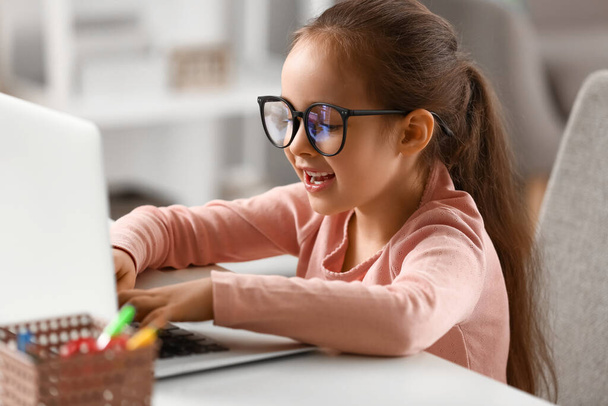 Petite écolière faisant des leçons en ligne à la maison - Photo, image