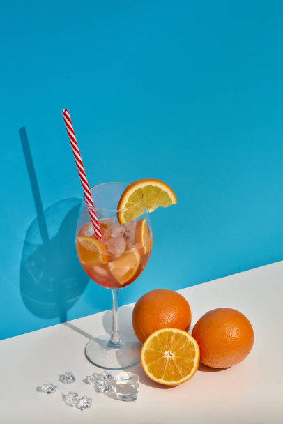 Cocktail. Fruit drink with ice and oranges on double white blue background with shadow. Copy space. Vertical orienntation. Orange juice - Fotografie, Obrázek