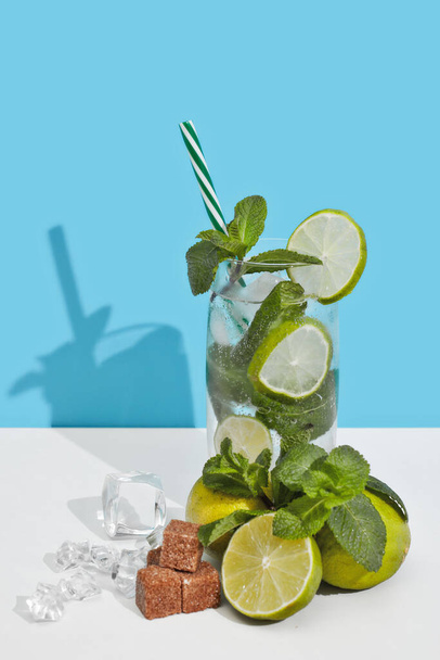 Mojito cocktail with lime, leaves of mint and pieces of sugar on double white blue background with shadow. - Foto, Imagen