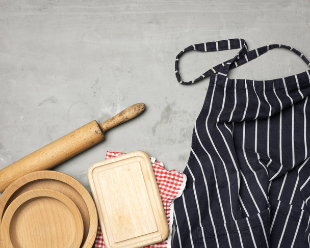 blue striped chef apron, wooden utensils on gray background, top view - Valokuva, kuva
