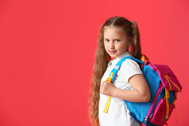 Kleine Schülerin mit Rucksack auf farbigem Hintergrund - Foto, Bild