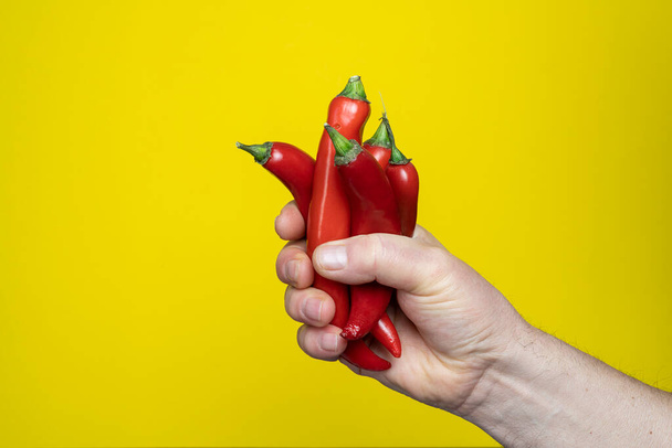 hand holding a red pepper on a yellow background - Φωτογραφία, εικόνα