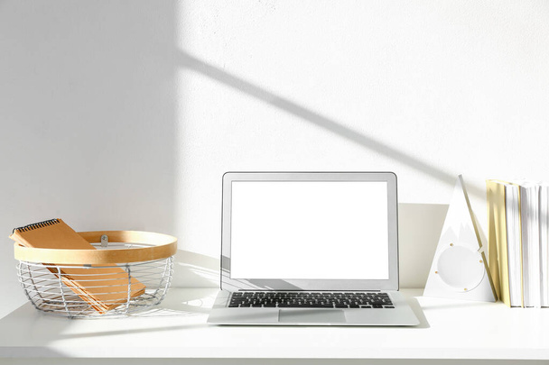 Moderner Arbeitsplatz mit Laptop nahe Lichtwand - Foto, Bild