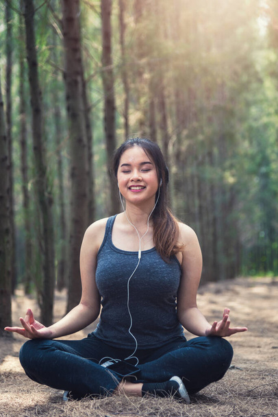 Beautiful young woman relaxation sitting meditation exercise yoga in morning at forest nature park - Foto, Imagem