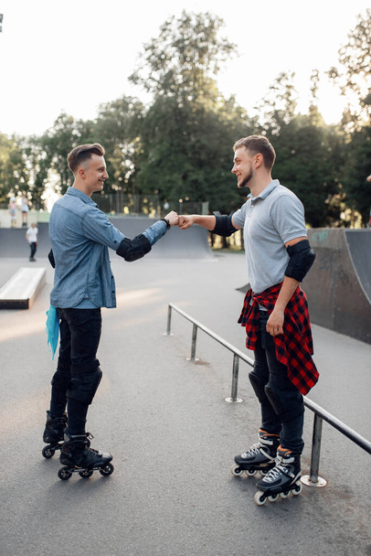 Roller skating, two male skaters rolling in summer park. Urban roller-skating, active extreme sport outdoors - Foto, Imagem