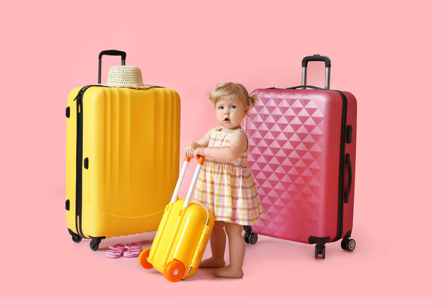 Schattig baby meisje met koffers op kleur achtergrond - Foto, afbeelding