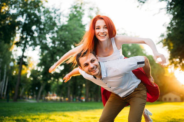 Young couple funs together in summer park. Romantic date of attractive woman and young man - Фото, зображення