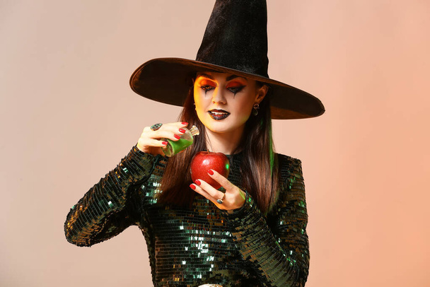 Joven bruja con manzana y poción sobre fondo de color - Foto, Imagen