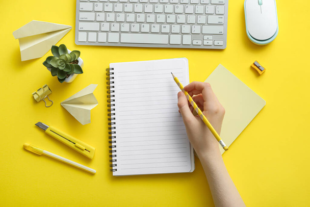 Frau mit Notizbuch und Computertastatur auf farbigem Hintergrund - Foto, Bild