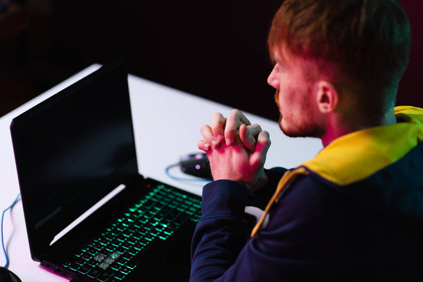Gamer playing video games with headphones on neon light background - Photo, Image