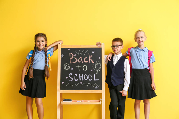 Χαριτωμένο μαθητές κοντά στο chalkboard στο φόντο χρώμα - Φωτογραφία, εικόνα