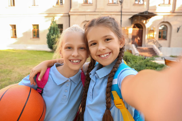 Niedliche kleine Schulmädchen mit Ball Selfie im Freien - Foto, Bild