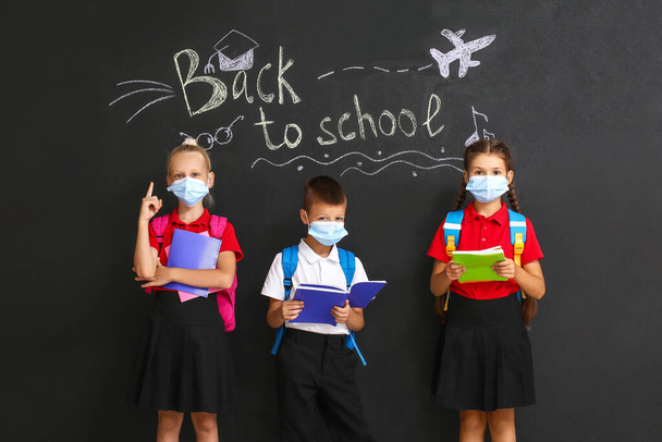 Aranyos diákok orvosi maszkok sötét háttér szöveggel vissza SCHOOL - Fotó, kép