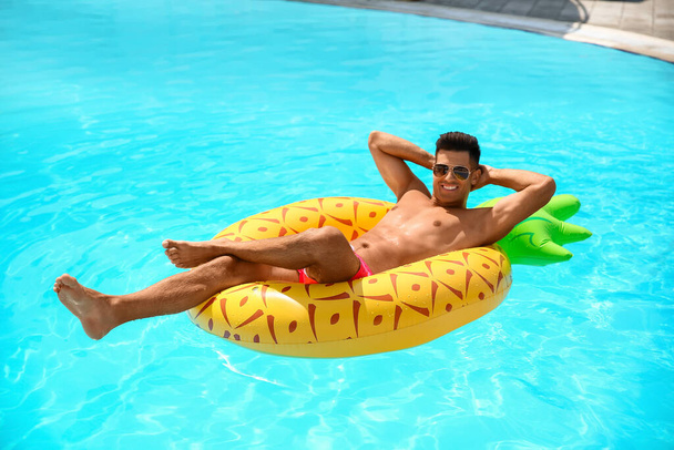 Handsome man with inflatable ring in swimming pool - Photo, image