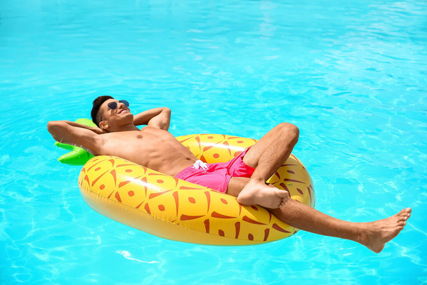 Красивий чоловік з надувним кільцем у басейні
 - Фото, зображення