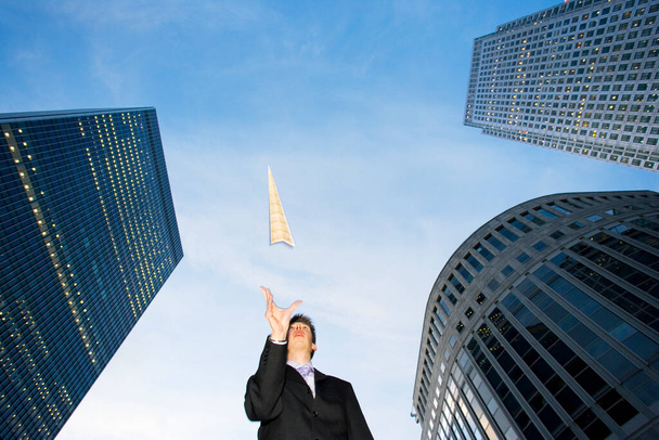 Low angle view of a caucasian businessman throwing a paper airplane - 写真・画像