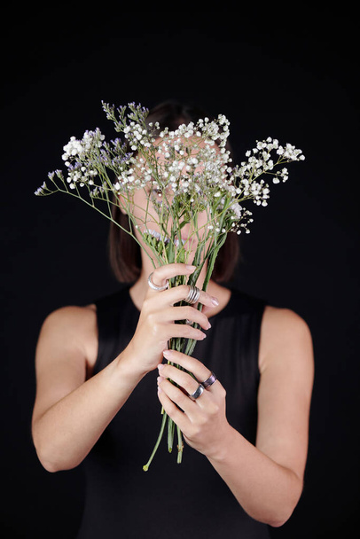 Γυναίκα σε ασημένια δαχτυλίδια κρατώντας λουλούδια - Φωτογραφία, εικόνα