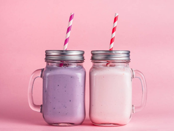 Strawberry and blueberry smoothie in mason jar glass on pink background. - Zdjęcie, obraz