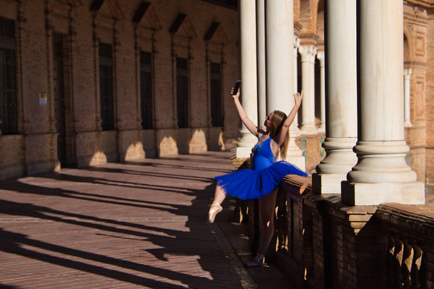 Classical ballet dancer taking a photo with her mobile phone on the railing of a park balcony. The dancer is in rehearsal for a ballet performance and is resting. - Foto, Bild