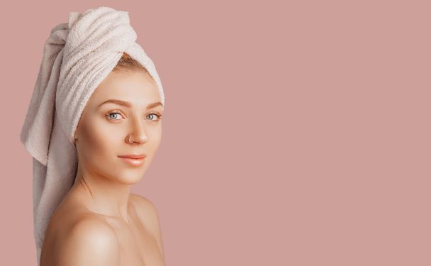 Beautiful sensual young girl with clean skin on a pink background with a mockup. Topless woman in a towel. The concept of spa treatments, natural beauty and care, youth, cream and mask, freshness - Valokuva, kuva