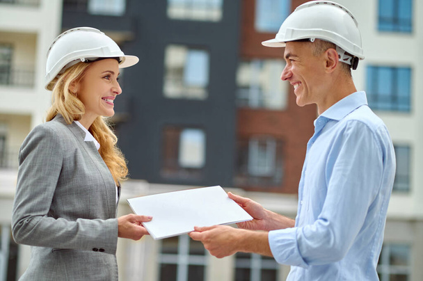 Supervisor handing over the building documentation to a joyous worker - Foto, immagini