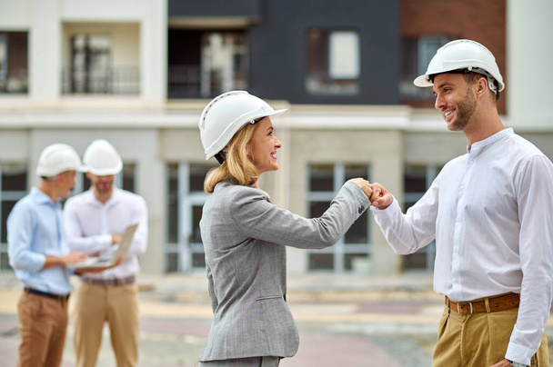 Two colleagues in safety helmets greeting each other - Foto, Imagen