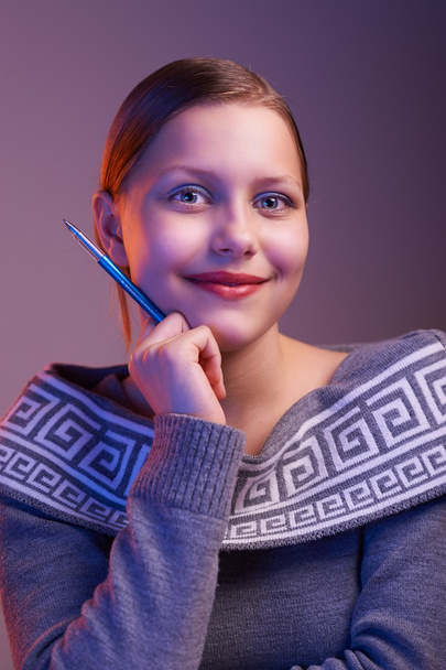 Teen girl smiling with pen in her hand, portrait - Foto, imagen