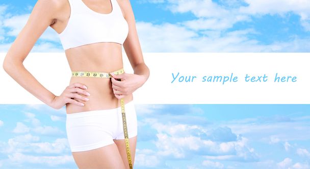 Slim girl with tape on sky background - Photo, Image