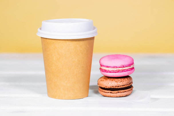 Coffee to go in paper eco cup with chocolate french macaroon on wooden and light orange background, Fast food, Copyspace, Caffeine Drink take away - Фото, изображение