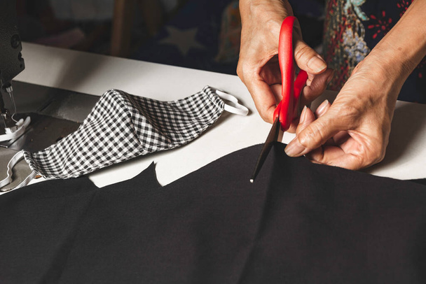 Woman cutting black fabric with scissors. Housework and lifestyle concept. - Foto, Imagem