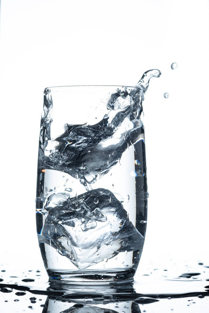 Water glass ice cube splash in vertical format and back lit - Foto, Imagen