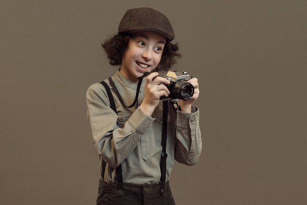 Portrait of a joyful boy in retro style. In his hands is a camera. Vintage stylization. - Foto, Bild