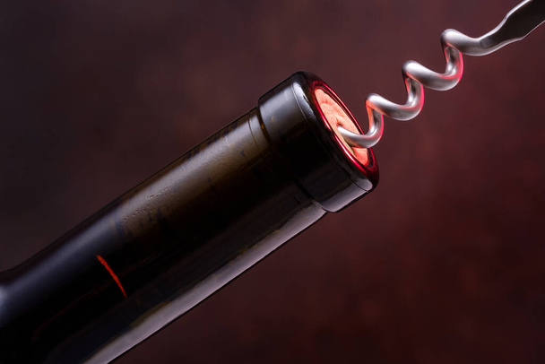 red wine bottle with a corkscrew on a black background - Foto, immagini