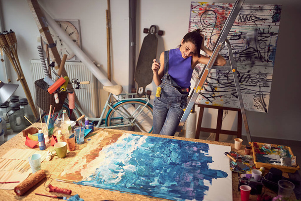 Cute female painter artist creating a new piece in the studio; Creative lifestyle concept - Фото, зображення