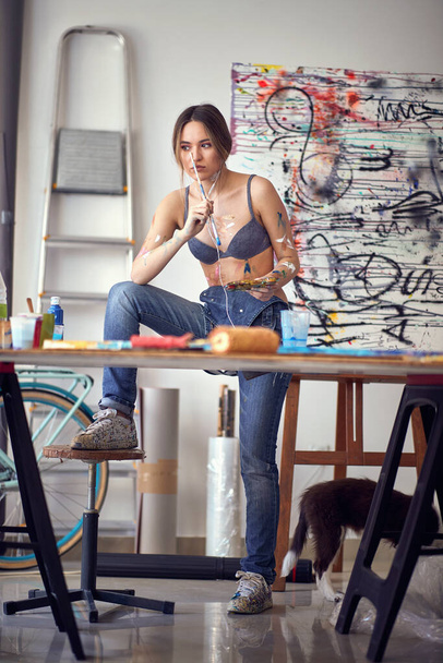 girl in underwear drawing with brush and colorful paints in studio. - 写真・画像