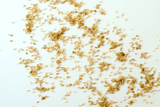 natürliche Körner von Bulgur-Getreide auf einer weißen Oberfläche verstreut - Foto, Bild